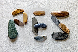 Word PEZ is written using colored stones on a white grainy surface
Translation: fish