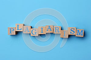 Word Plagiarism made of wooden cubes with letters on light blue background, top view