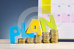 Word PLAN and stacking coins on wooden desk over beautiful reverberation gradient background