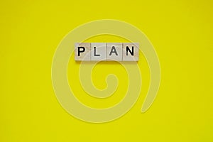 Word plan. Top view of wooden blocks with letters on yellow surface