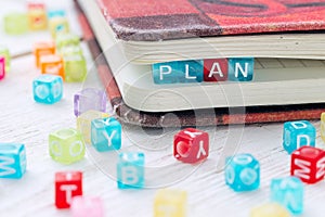 Word PLAN written on a colored block in a book.