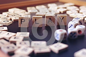 Word PLAY with wooden letters on black Board with dice and letter in the circle