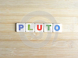 Word Pluto on wood background