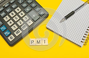 Word pmi made with wood letters on yellow background and modern calculator with pen and notebook. Copy space. Economy, money