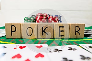 The word poker on wooden cubes, poker chips with playing cards on the green casino table