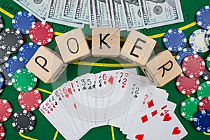 The word poker on wooden cubes, poker chips with playing cards on the green casino table