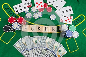 The word poker on wooden cubes, poker chips with playing cards on the green casino table
