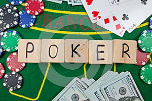 The word poker on wooden cubes, poker chips with playing cards on the green casino table