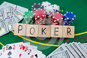 The word poker on wooden cubes, poker chips with playing cards on the green casino table