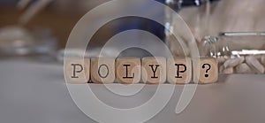 Word POLYP and question mark composed of wooden dices. Pills, documents and a pen in the background photo