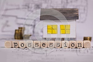 Word POSSESSION composed of wooden letter. Small paper house in the background photo