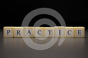 The word PRACTICE written on wooden cubes isolated on a black background