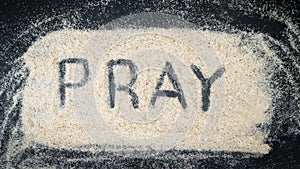 Word PRAY written on white sand