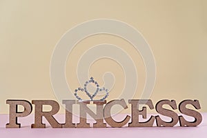 Word Princess abstract wooden letters. Pink background with sparkling crown.