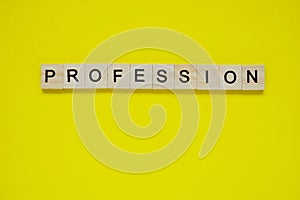 Word profession. Top view of wooden blocks with letters on yellow surface