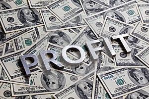 The word PROFIT laid with aluminium letters on the US dollar banknotes background - with selective focus