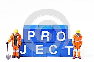 Two blue collar figurines standing next to the word `project` photo
