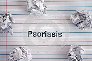 Word Psoriasis on notebook sheet with some crumpled paper balls