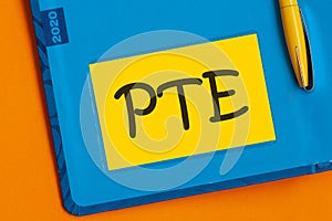 The word PTE is written in black marker on the yellow paper for notes. Pearson Tests of English PTE concept Foreign Language exams