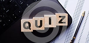 The word QUIZ is written in red on wooden cubes on the keyboard next to the pen