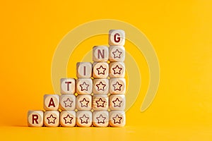 The word rating with increasing performance stars on wooden cubes against yellow background. Improvement in service rating and