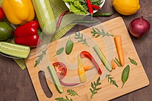 Word Raw written with letters from different raw vegetables, fruits and greens on wooden cutting board. Organic ingredients