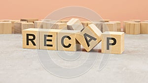 word Recap made with wood blocks. text is written in black letters, light background