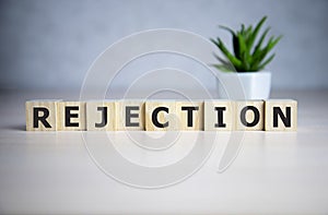 The word REJECTION, spelt with wooden letter tiles over a blue background photo