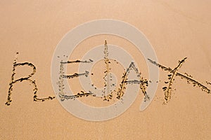 Word Relax hand written in the sand. Close up sand texture on beach in summer. Vacation, holiday concept