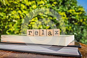 The word RELAX, letters cubes on books with green trees, nature background