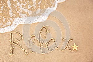 Word `RELAX` written on sandy beach