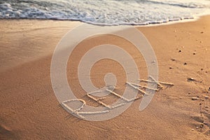Word Relax written on sandy beach in summer