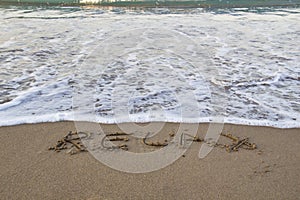 Word RELAX wrote on the sand against background. Message says