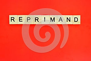 Word reprimand. Top view of wooden blocks with letters on red surface