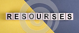 Word RESOURSES on wooden cubes on yellow - gray background