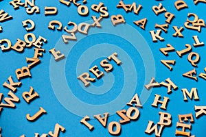 Word REST made out of wooden letters on bright blue background. Motivational Words Quotes Concept.