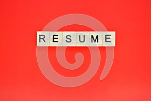 Word resume. Top view of wooden blocks with letters on red surface