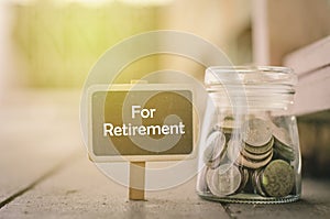 Word RETIREMENT on wooden signage and coin in jar .fade color effect wooden background with light effect