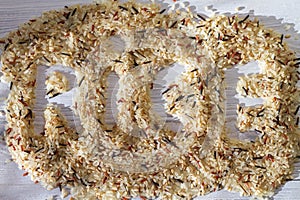 The word rice on a wooden surface of rice grains. The background is from a mixture of wild, brown, red, white rice