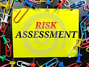 Word RISK ASSESSMENT on colorful paper with paper clips on black background.