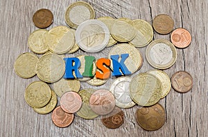 The word `risk` laid out from letters / coins on a wooden background. The concept of economic risk.