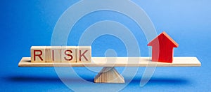 The word risk and a miniature house on the scales. The concept of mortgage, loans and real estate. Taxes and debts. Property