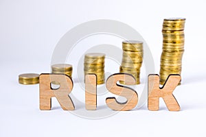 Word risk of three-dimensional letters is in foreground with growth columns of coins on blurred background. Risk concept for finan