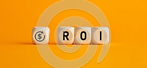 The word ROI return on investment written on wooden cubes with on yellow background. Profit or loss analysis in business and