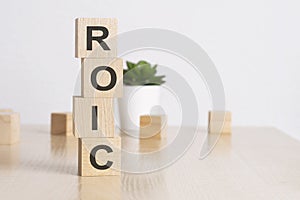 word ROIC with wood building blocks, light green background. front view.