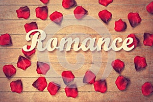 Word Romance and petals on wooden table.