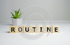 Word routine is made up of square wooden letters on a gray background