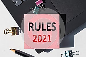 The word RULES 2021 on a notebook shown by a business woman
