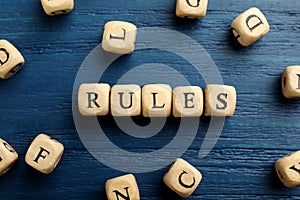 Word Rules made of cubes with letters on blue wooden table, flat lay