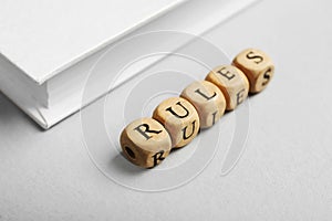 Word Rules made of wooden cubes with letters and book on white table